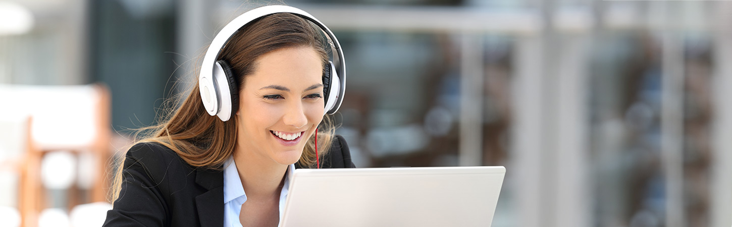 young woman with headphones watching webinar on laptop