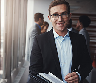 smiling confident businessman with pen to pad